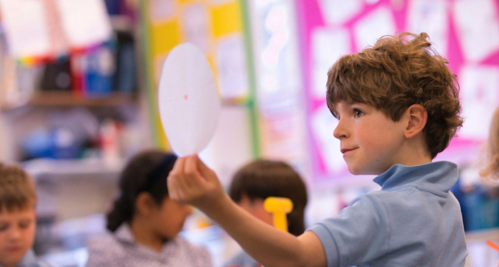Image of a boy in class holding up a piece of paper